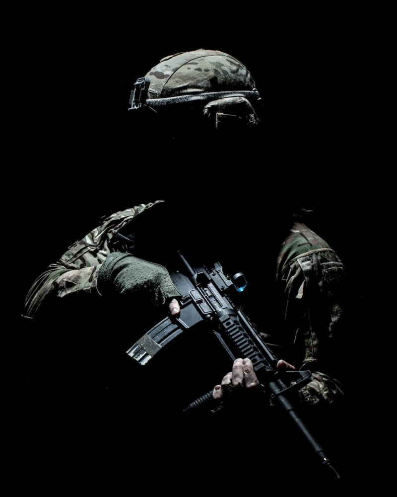 man in black and green camouflage suit holding rifle