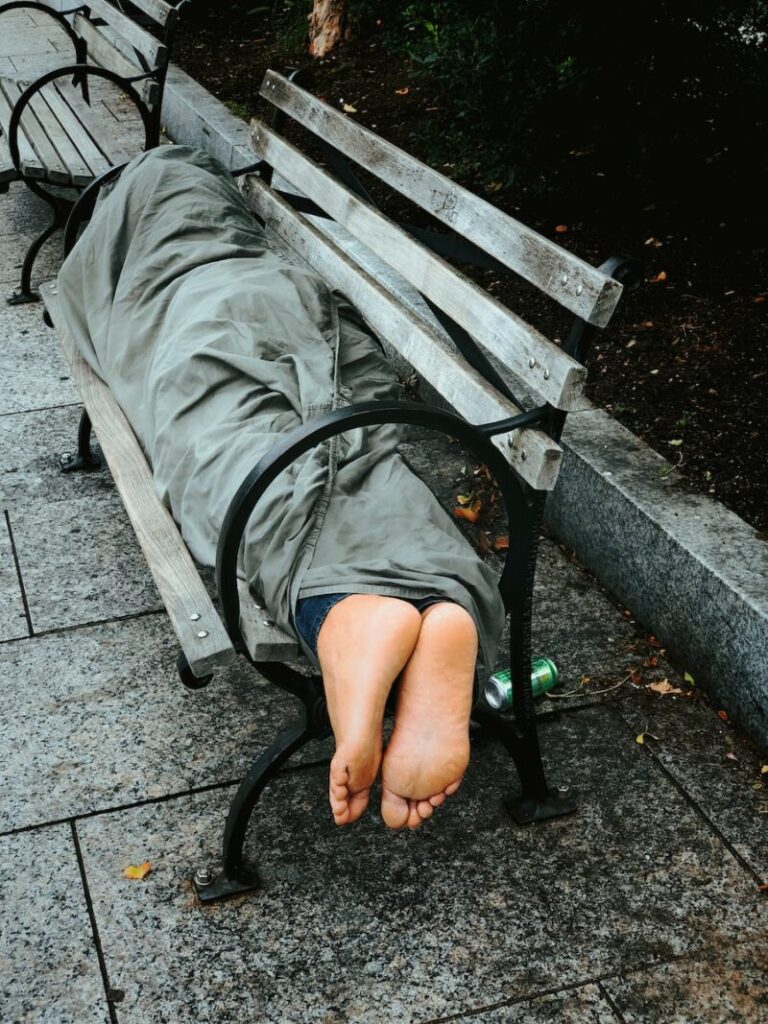 person sleeping on bench covered with gray blanket